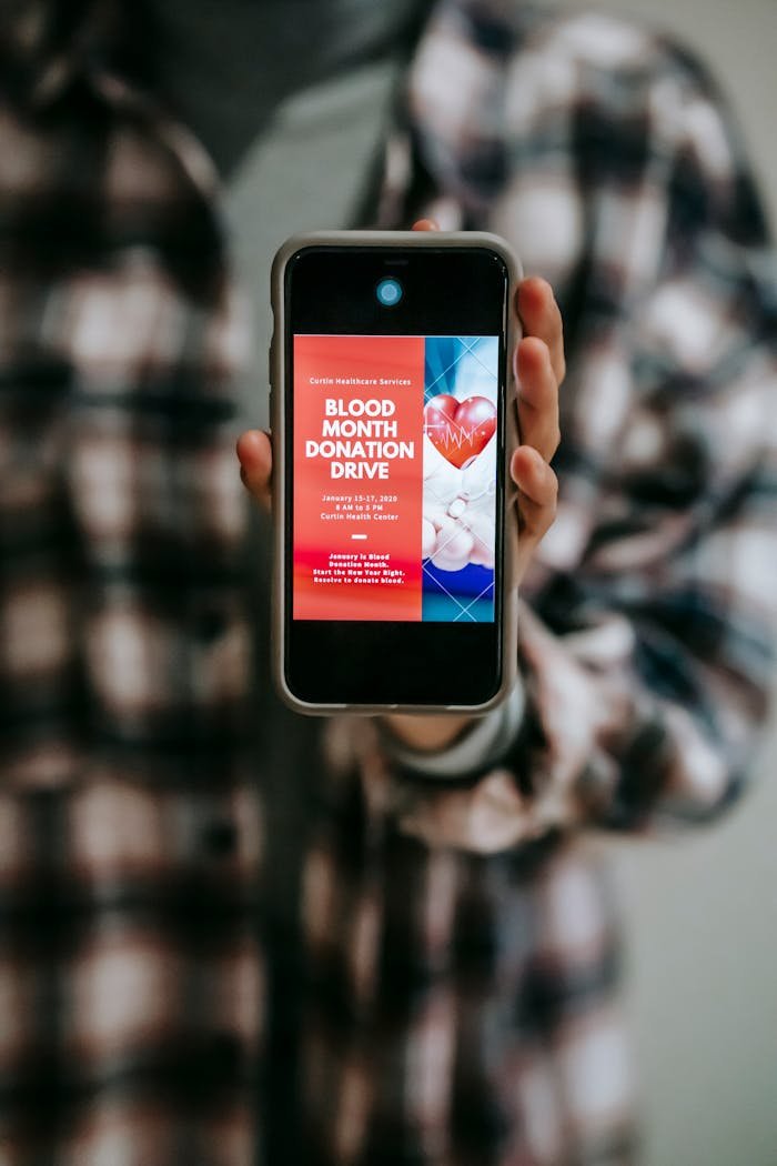 impact-img A smartphone displaying a blood donation drive advertisement held by a person.